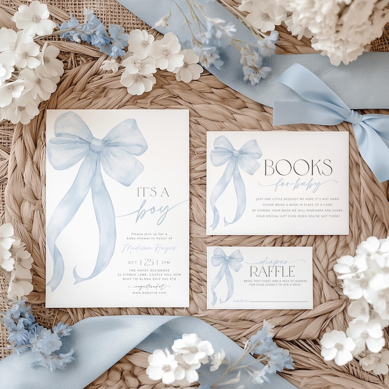 May include: Blue and white baby shower invitation with a watercolor bow, the text "It's a boy" and the words "Books for baby" on a separate card. The invitation includes the date, time, and location of the event. There is also a card for a diaper raffle.