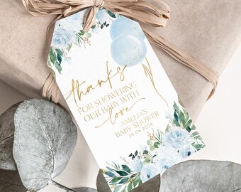 May include: A white thank you tag with gold lettering and blue watercolour flowers. The text reads "Thanks for showering our baby with love Amelia's Baby Shower 30.06.2024".
