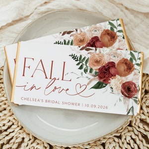May include: Fall in love bridal shower favor chocolate bar wrappers with a floral design in shades of peach, pink, and burgundy. The text reads "Fall in love" with a heart and "Chelsea's Bridal Shower | 10.09.2026".