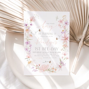 K&ouml;nnte beinhalten: Eine Einladung im floralen Design f&uuml;r eine erste Geburtstagsfeier. Die Einladung zeigt einen Kranz aus Aquarellblumen, Bienen und den Text "our little honey is turning 1! please join us for Penelope's 1st bee-day. Saturday August 25th at 2pm. Castle Hill Heritage Park. 223 Heritage Park Dr. Castle Hill. Michelle 0412 345 678"