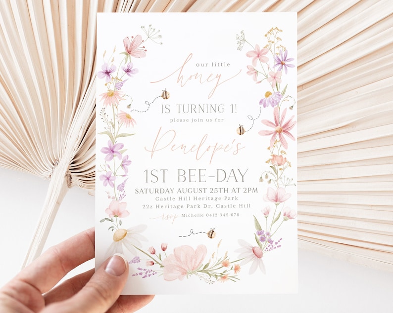 K&ouml;nnte beinhalten: Eine Einladung zu einer ersten Geburtstagsfeier mit Blumendekor f&uuml;r ein M&auml;dchen namens Penelope. Die Einladung zeigt einen Kranz aus Aquarellblumen, Bienen und den Text "Unser kleiner Honig wird 1! Bitte seid dabei f&uuml;r Penelopes 1. Bienentag. Samstag, 25. August um 14:00 Uhr. Castle Hill Heritage Park. 22z Heritage Park Dr. Castle Hill. RSVP Michelle 0412 345 678."