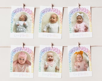 Può includere: Sei carte colorate con bordi arcobaleno e palloncini pastello. Ogni carta presenta un bambino in diversi abiti ed età, con il testo "One Month", "Two Months", "Three Months", "Four Months", "Five Months" e "Six Months" stampato sotto ogni foto.