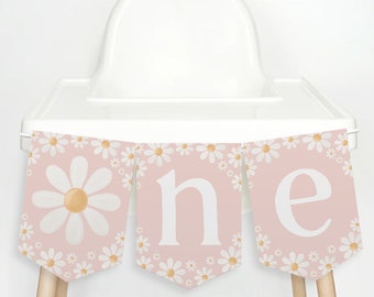 Op de afbeelding: Roze en witte hoge stoel banner met een madeliefjespatroon en het woord "one" in witte letters.