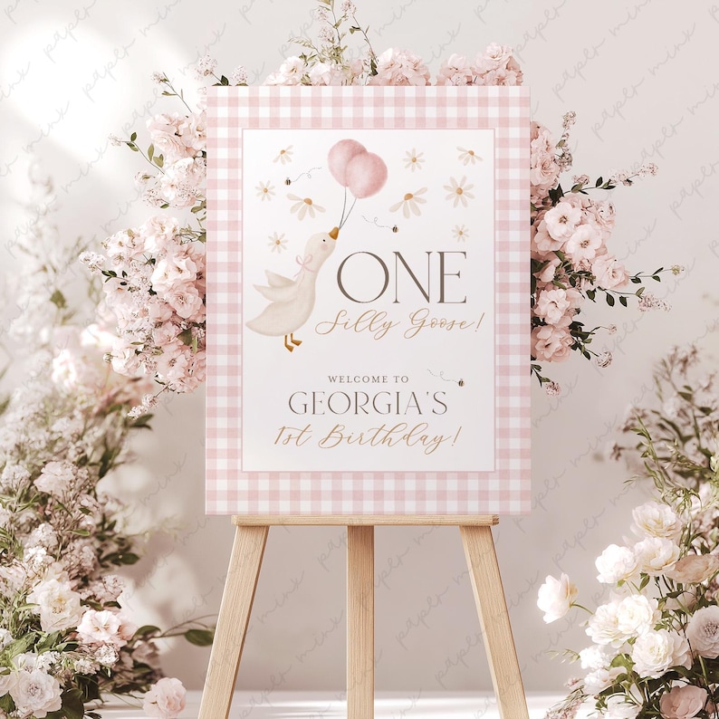 May include: A pink and white gingham welcome sign with a cartoon goose holding pink balloons. The sign reads "One Silly Goose! Welcome to Georgia's 1st Birthday!"
