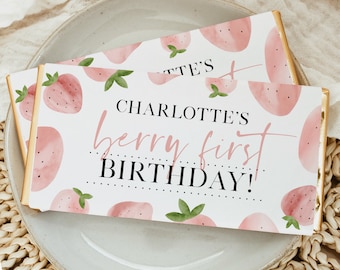 May include: White chocolate bar wrapper with a pink watercolor strawberry design. The text on the wrapper reads "Charlotte's Berry First Birthday!"