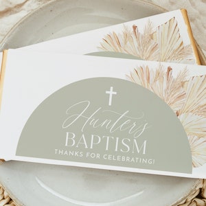 May include: White favor box with a green and white semi-circle design. The box has a cross and the text "Hunter's Baptism" and "Thanks for celebrating!"
