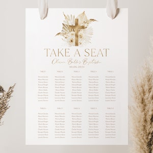 Peut inclure: Un plan de table imprimable blanc avec du texte doré pour un baptême. Le tableau comporte une croix dorée avec des fleurs blanches et de la verdure en haut. Le texte indique "Take a Seat" et "Olivia Belk's Baptism" avec la date "30.06.2021". Le tableau liste les tables 1 à 10 avec les noms des invités.