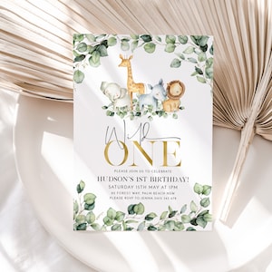 May include: A white invitation with a gold border and green leaves. The text reads "Wild One" in gold letters. The invitation is for Hudson's 1st birthday party. The party is on Saturday, May 15th at 1 PM. The address is 82 Forest Way, Palm Beach NSW. The RSVP number is 0412 345 678.