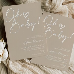 May include: Two beige baby shower invitations with white calligraphy that reads "Oh Baby!" and includes details for the event, including the date, time, location, and contact information.