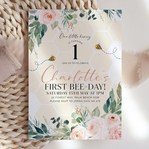 May include: A birthday invitation featuring the text "Our little honey is turning 1" and "Charlotte's FIRST BEE-DAY!". The design incorporates watercolor roses, greenery, and a honeycomb pattern with a bee illustration. The invitation is for a first birthday celebration.