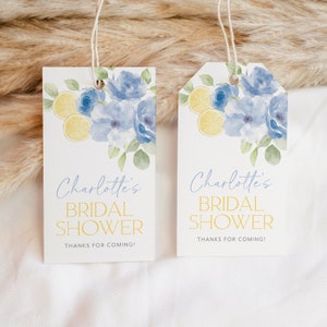 May include: Two white gift tags with blue watercolor flowers and yellow lemons. The text on the tags reads "Charlotte's Bridal Shower Thanks for coming!"