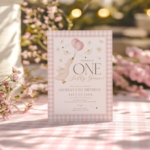 May include: Pink and white gingham patterned invitation with a cartoon goose holding pink balloons. The text reads "Georgia is One Silly Goose!" and includes details for Georgia's 1st birthday party.