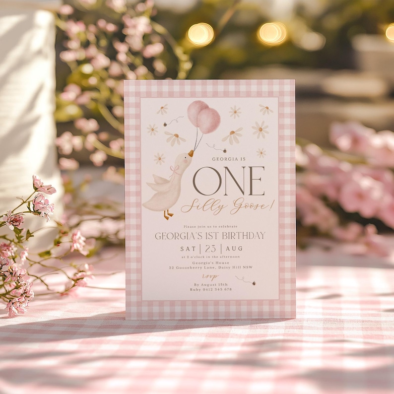 May include: Pink and white gingham patterned invitation with a cartoon goose holding pink balloons. The text reads "Georgia is One Silly Goose!" and includes details for Georgia's 1st birthday party.