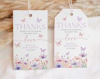 Op de afbeelding: Twee witte bedankkaartjes met een bloemenmotief en vlinders. De tekst op de kaartjes luidt "Bedankt voor het verwennen van onze baby met liefde" en "Selena's Baby Shower 12.05.2026".