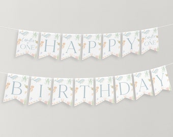 Peut inclure: Une bannière blanche et bleue avec un motif sur le thème de la mer. La bannière indique "Happy Birthday" avec les mots "Camilla is One" aux extrémités.