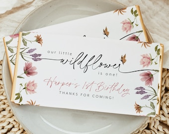 May include: A white chocolate bar wrapper with a floral design and the text "our little wildflower is one! Harper's 1st Birthday Thanks for coming!"
