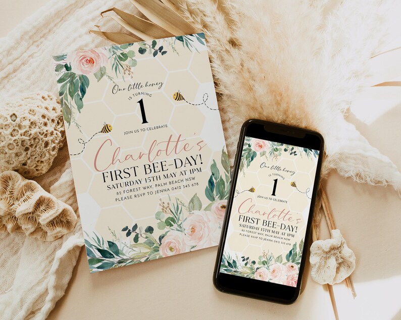 May include: A birthday invitation and a smartphone displaying the same design. The invitation features floral accents, a honeycomb background, and the text "Charlotte's First Bee-Day!" with a bee graphic. The phone shows the same design.