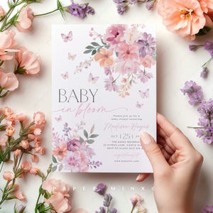 May include: A baby shower invitation featuring a floral design in shades of pink, purple, and peach. The text reads "Baby in Bloom" and includes the name "Madison Hayes" and the date "Oct 25, 2P".
