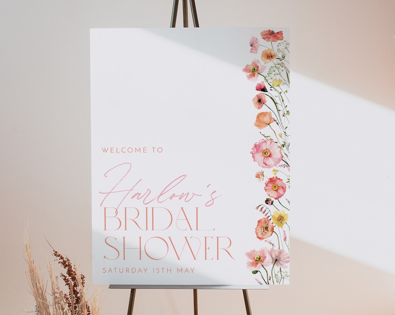 Pu&ograve; includere: Un cartello di benvenuto bianco con testo rosa che recita "Benvenuti al Bridal Shower di Harlow Sabato 15 maggio". Il cartello &egrave; decorato con una linea verticale di fiori ad acquerello rosa e arancioni.