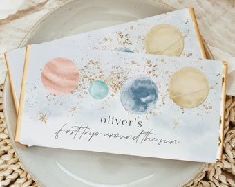 May include: A white card with a watercolor illustration of planets and stars. The text "Oliver's first trip around the sun" is written in black cursive.