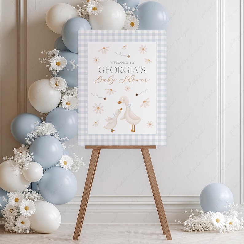 K&ouml;nnte beinhalten: Ein Willkommenszeichen f&uuml;r eine Babyparty mit einem blau-wei&szlig; karierten Hintergrund. Das Schild zeigt zwei wei&szlig;e G&auml;nse mit einem Blumenmuster und dem Text "Willkommen zur Babyparty von Georgia".