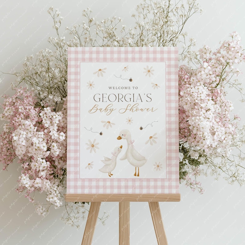 May include: A pink and white gingham welcome sign with the text "Welcome to Georgia's Baby Shower" and a watercolour illustration of two geese with daisies and bees.