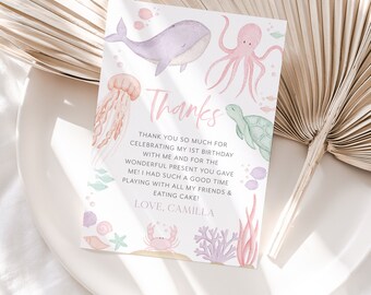 May include: A pink and blue thank you card with an illustration of an octopus, whale, jellyfish, turtle, and crab. The text on the card reads "Thanks" and "Thank you so much for celebrating my 1st birthday with me and for the wonderful present you gave me! I had such a good time playing with all my friends & eating cake! Love, Camilla."