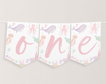 May include: A pink and white banner with the word "one" written in pink script. The banner is decorated with a sea-themed pattern of whales, jellyfish, octopuses, and sea turtles.