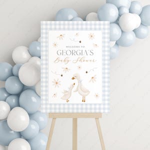 K&ouml;nnte beinhalten: Ein blaues und wei&szlig;es Gingham-Babyparty-Schild mit dem Text "Willkommen zur Babyparty von Georgia" und einer Aquarell-Illustration von zwei Enten mit Blumen und Bienen.