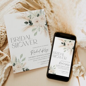 Op de afbeelding: Een digitale en gedrukte uitnodiging voor een bruidsdouche met een aquarelbloemendesign met pampasgras en witte bloemen. De tekst op de uitnodiging luidt "Bridal Shower" en "Wordt u alstublieft uitgenodigd om Rachel King te eren".