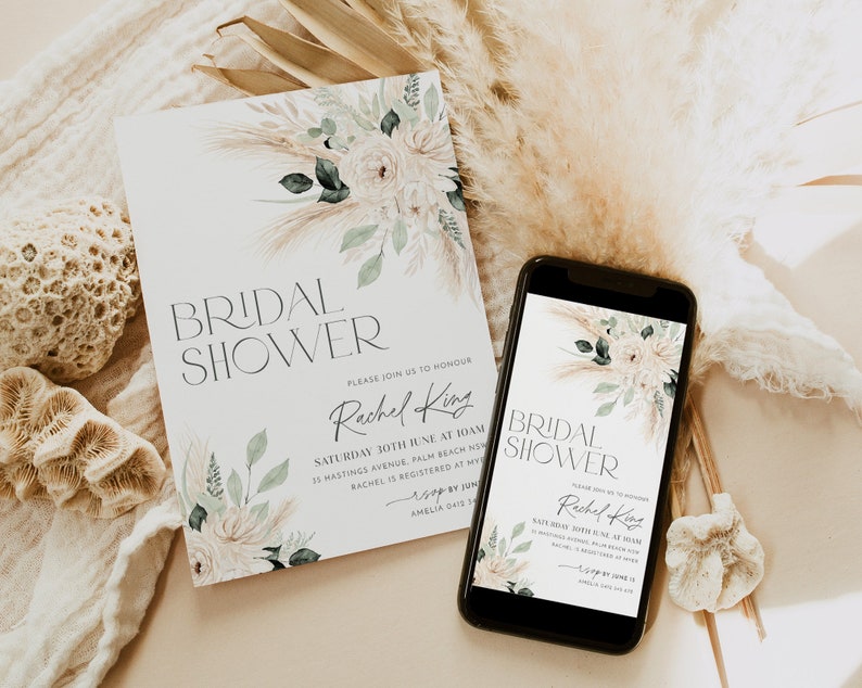 Op de afbeelding: Een digitale en gedrukte uitnodiging voor een bruidsdouche met een aquarelbloemendesign met pampasgras en witte bloemen. De tekst op de uitnodiging luidt "Bridal Shower" en "Wordt u alstublieft uitgenodigd om Rachel King te eren".