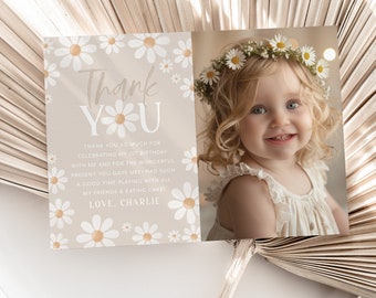 May include: A thank you card with a daisy pattern and a photo of a young girl wearing a daisy crown. The text on the card reads "Thank YU" and includes a message thanking guests for celebrating the child's first birthday.