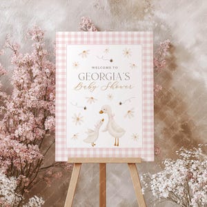 May include: Pink and white gingham baby shower sign with the text "Welcome to Georgia's Baby Shower" and a watercolour illustration of two ducks with flowers and bees.