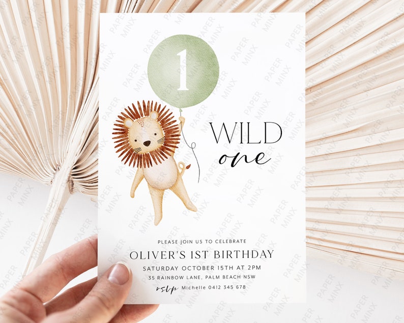 May include: A green balloon with the number "1" on it is held by a cartoon lion. The text "WILD one" is written in black lettering. The invitation reads "Please join us to celebrate Oliver's 1st Birthday, Saturday October 15th at 2pm, 35 Rainbow Lane, Palm Beach NSW, rsvp Michelle 0412 345 678".