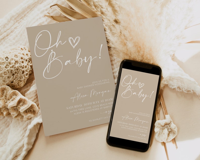 May include: A beige baby shower invitation with white calligraphy that reads "Oh Baby!"  The invitation includes the name "Alexa Morgan" and details for the event. A matching digital invitation is displayed on a smartphone.