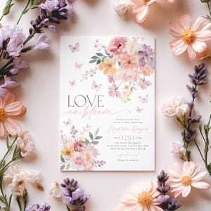 Op de afbeelding: Een bloemige bruidsdouche-uitnodiging met vlinders en de tekst "LOVE in bloom" in roze schrift. De uitnodiging is voor Madison Hayes en bevat de datum, tijd en locatie van de douche. De tekst "Target & Amazon" staat onderaan de uitnodiging.