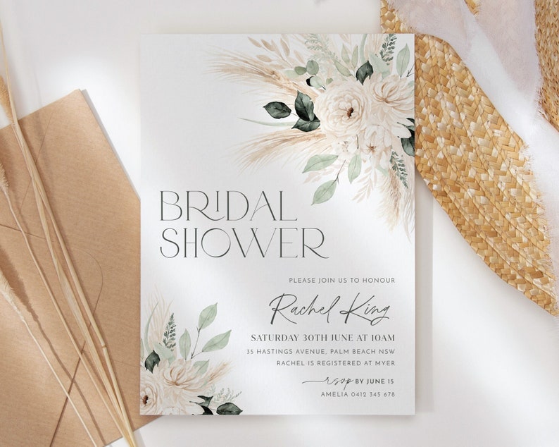 Op de afbeelding: Een witte kaart met een bloemenontwerp en de tekst "BRIDAL SHOWER" in het zwart. De tekst "PLEASE JOIN US TO HONOUR Rachel King" is in zwarte cursieve letters geschreven. De tekst "SATURDAY 30TH JUNE AT 10AM 35 HASTINGS AVENUE, PALM BEACH NSW RACHEL IS REGISTERED AT MYER RSVP BY JUNE 15 AMELIA 0412 345 678" is in het zwart geschreven.