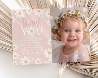 May include: Pink thank you card with a daisy pattern and the text "Thank YU". The card has a photo of a young girl wearing a daisy crown and a pink dress. The text on the card reads "Thank you so much for celebrating my 1st birthday with me and for the wonderful present you gave me! I had such a good time playing with all my friends & eating cake! Love, Charlie"