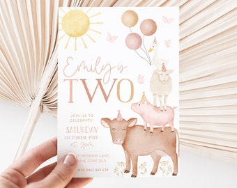 Puede incluir: Una invitación de cumpleaños rosa y dorada con el texto "Emily is TWO" y una ilustración de acuarela de animales de granja, incluyendo una vaca, un cerdo, una oveja y un ganso. La invitación también incluye un sol, mariposas y globos.