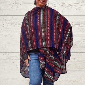 May include: A colorful poncho with vertical stripes in red, blue, and teal. The poncho is draped over the shoulders and has a flowing design. The pattern includes small geometric shapes and lines.