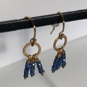 Puede incluir: Pendientes de aro de oro con cuentas de piedras preciosas azules colgantes.