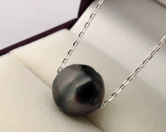 May include: A dark gray pearl pendant necklace. The large, irregularly shaped pearl is suspended from a delicate silver chain. The necklace is presented in a maroon jewelry box with a cream-colored interior.