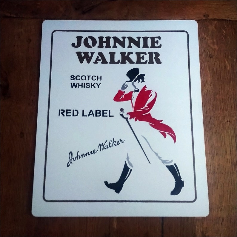 May include: White metal sign with a black and red illustration of a man in a top hat and a red jacket walking with a cane. The sign reads "JOHNNIE WALKER SCOTCH WHISKY RED LABEL Johnnie Walker"