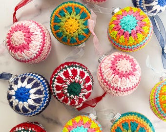 May include: A collection of colorful crocheted Christmas ornaments with various geometric patterns. The ornaments are made with different colored yarns, including red, green, blue, yellow, pink, and white.