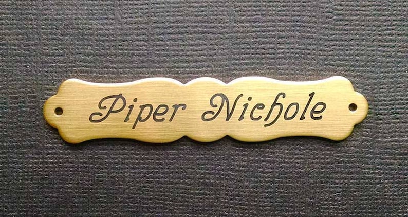 Może przedstawiać: Metalowa tabliczka z nazwiskiem w kolorze złotym z wygrawerowanym czarnym tekstem "Piper Nichole".