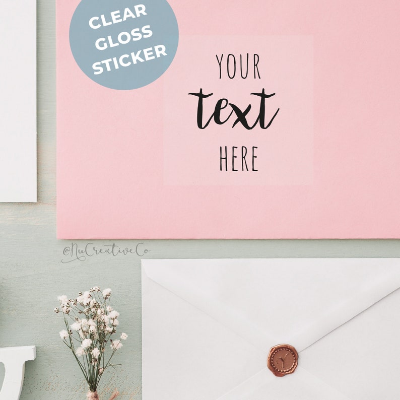 K&ouml;nnte beinhalten: Eine rosa Karte mit einem transparenten Glanzaufkleber, auf dem "YOUR text HERE" steht. Der Aufkleber befindet sich auf einem rosa Hintergrund. Die Karte liegt auf einer hellblauen Oberfl&auml;che.