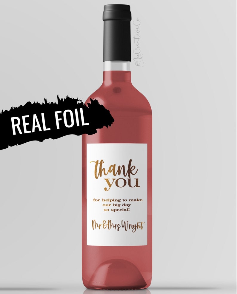 May include: A rose wine bottle with a white label that says "thank you" in gold lettering. The label also includes the text "for helping to make our big day so special! Mr&Mrs Wright".