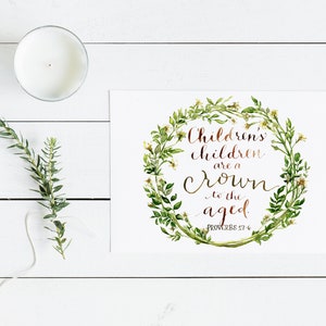 May include: A white candle in a glass container, a sprig of greenery, and a print with the text "Children's children are a crown to the aged" in a floral wreath. The print includes the Bible verse Proverbs 17:6.