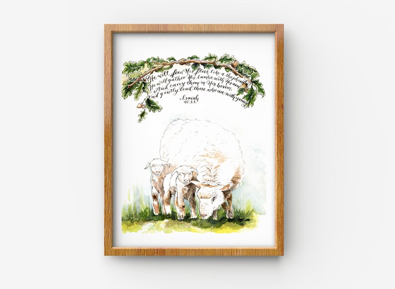 May include: Watercolor painting of a white sheep with two lambs. The painting is framed in a light wood frame. The text "He will feed his flock like a shepherd. He will gather his lambs with his arm. And carry them in his bosom, and gently lead those who are with young." is written in calligraphy above the sheep.