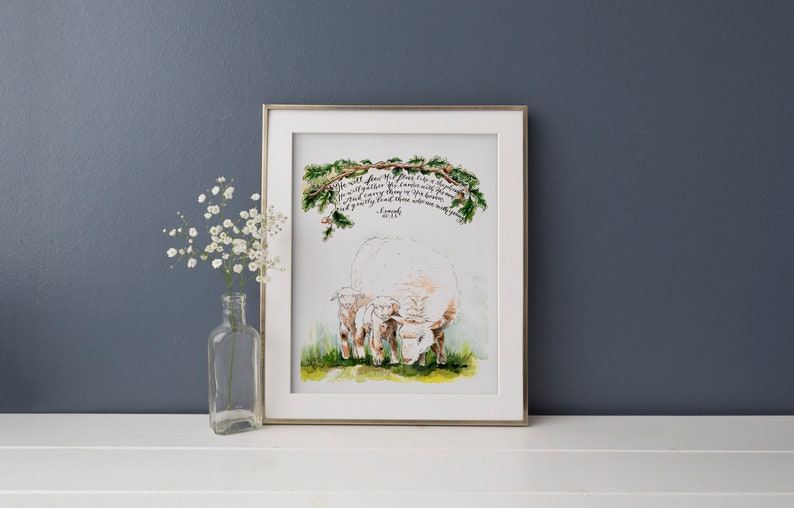 May include: A watercolor painting of a white sheep and two lambs with a green leafy branch above them. The painting includes the text "He will feed His flock like a shepherd. He will gather the lambs in His arms and carry them close to His heart; gently will He lead those that are with young." - Isaiah 40:11